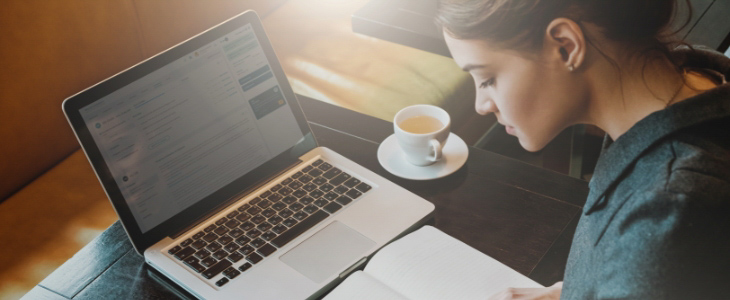 profile of woman sitting at desk with laptop and tea