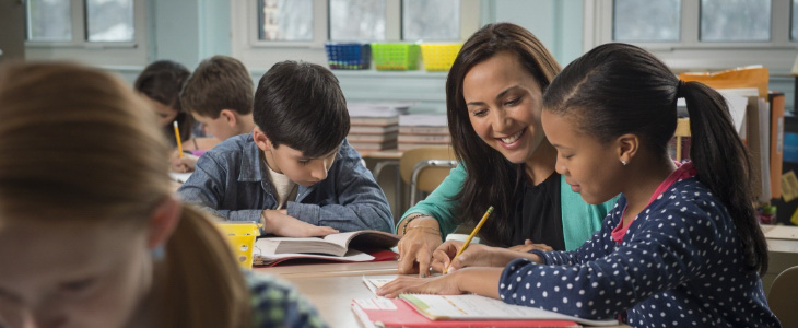 teacher smiling working with students at their desks